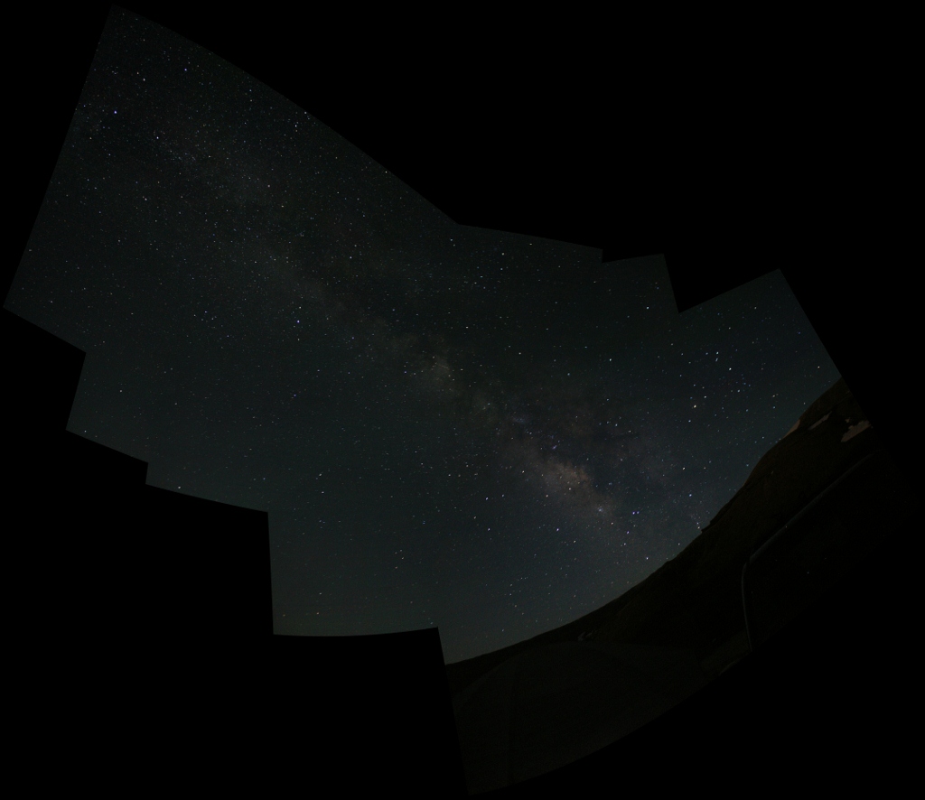 a pano of the milky way, with tent and car at the bottom